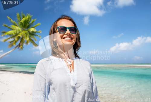 Image of happy smiling woman in sunglasses over beach