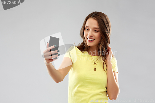 Image of smiling teenage girl taking selfie by smartphone