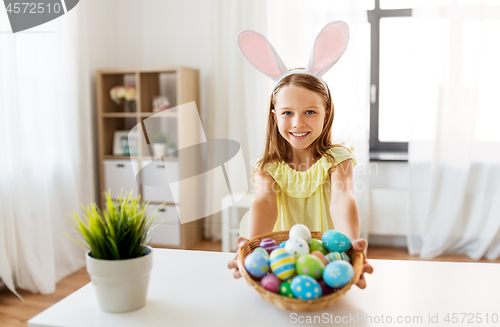 Image of happy girl with colored easter eggs at home