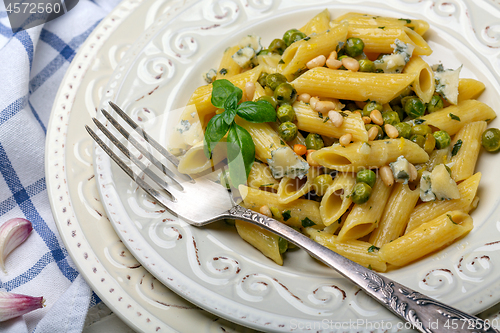 Image of Penne pasta with green peas close up.