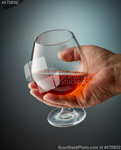 Image of glass of cognac in human hand