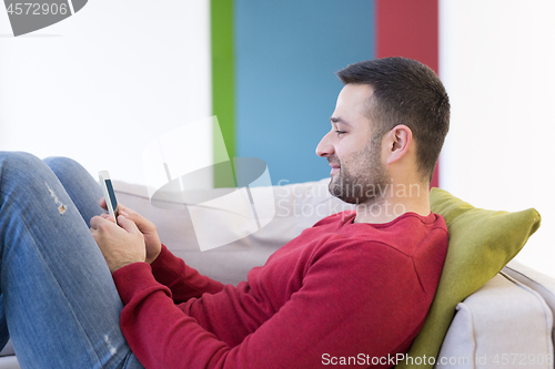 Image of young man using a mobile phone  at home