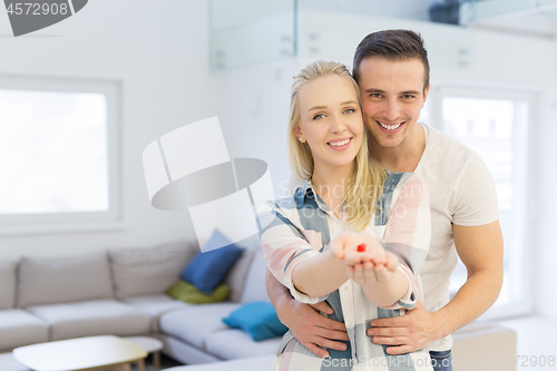 Image of couple showing small red house in hands