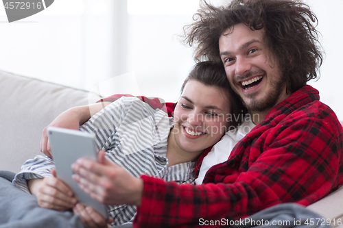 Image of couple relaxing at  home with tablet computers