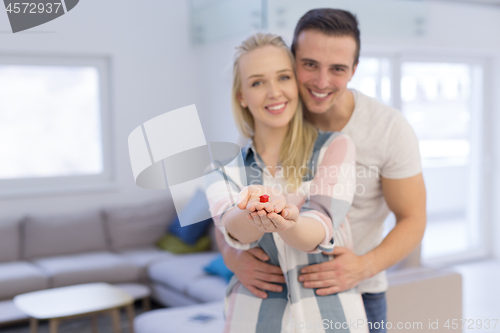 Image of couple showing small red house in hands