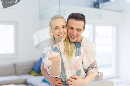 Image of couple showing small red house in hands