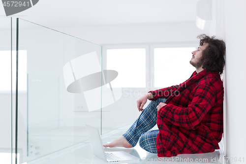 Image of young freelancer in bathrobe working from home