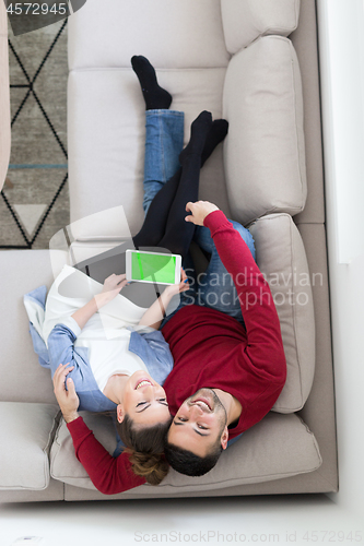 Image of couple relaxing at  home with tablet computers