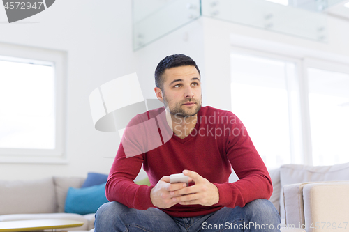 Image of young man using a mobile phone  at home