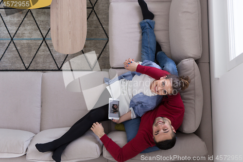 Image of couple relaxing at  home with tablet computers