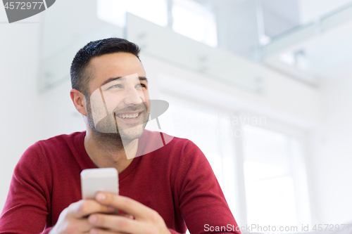 Image of young man using a mobile phone  at home