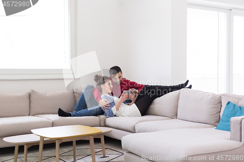 Image of couple relaxing at  home with tablet computers