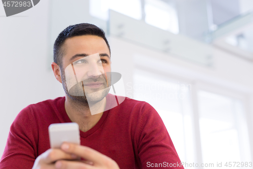 Image of young man using a mobile phone  at home