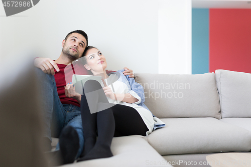 Image of couple relaxing at  home with tablet computers