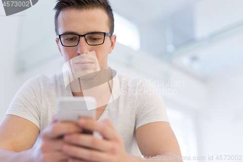 Image of young man using a mobile phone  at home