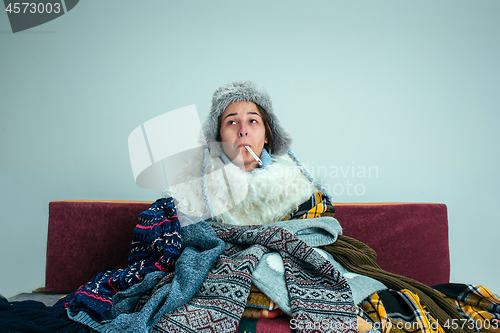 Image of The young woman with Flue Sitting on Sofa at Home. Healthcare Concepts.