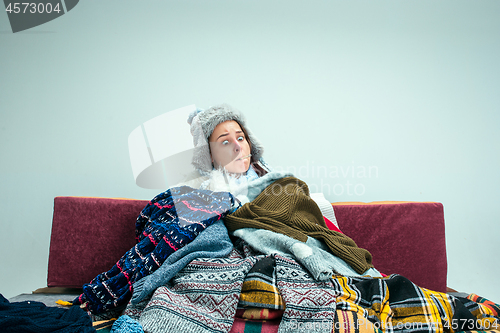 Image of The young woman with Flue Sitting on Sofa at Home. Healthcare Concepts.