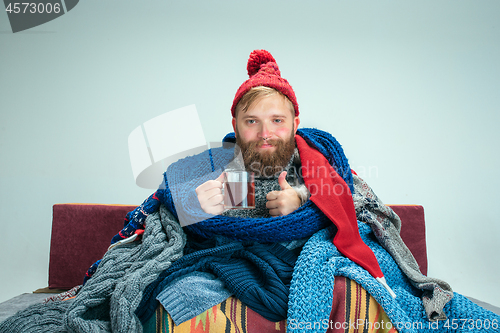 Image of Bearded Man with Flue Sitting on Sofa at Home. Healthcare Concepts.