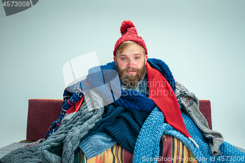 Image of Bearded Man with Flue Sitting on Sofa at Home. Healthcare Concepts.