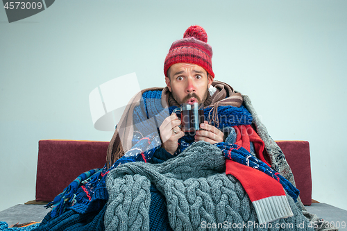 Image of Bearded Man with Flue Sitting on Sofa at Home. Healthcare Concepts.