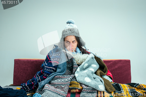 Image of The young woman with Flue Sitting on Sofa at Home. Healthcare Concepts.