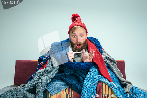 Image of Bearded Man with Flue Sitting on Sofa at Home. Healthcare Concepts.