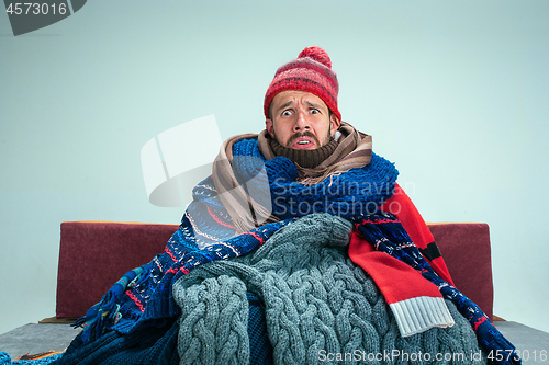 Image of Bearded Man with Flue Sitting on Sofa at Home. Healthcare Concepts.