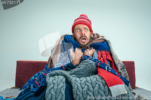 Image of Bearded Man with Flue Sitting on Sofa at Home. Healthcare Concepts.