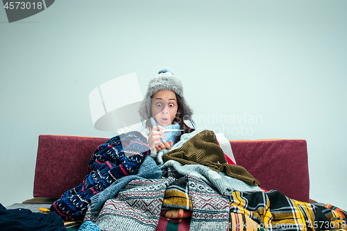 Image of The young woman with Flue Sitting on Sofa at Home. Healthcare Concepts.