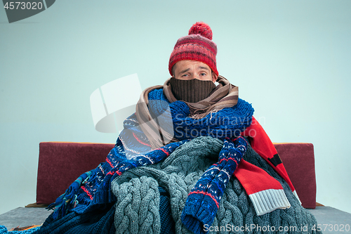 Image of Bearded Man with Flue Sitting on Sofa at Home. Healthcare Concepts.