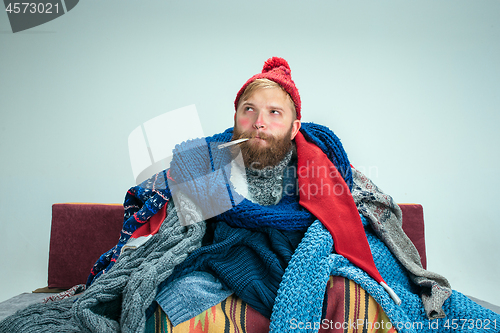 Image of Bearded Man with Flue Sitting on Sofa at Home. Healthcare Concepts.