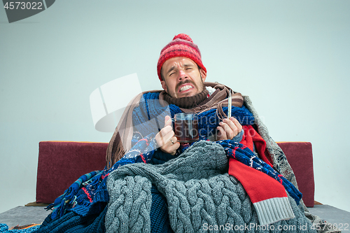 Image of Bearded Man with Flue Sitting on Sofa at Home. Healthcare Concepts.