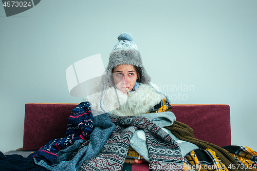 Image of The young woman with Flue Sitting on Sofa at Home. Healthcare Concepts.