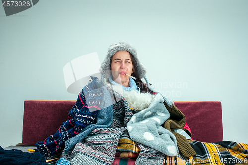 Image of The young woman with Flue Sitting on Sofa at Home. Healthcare Concepts.