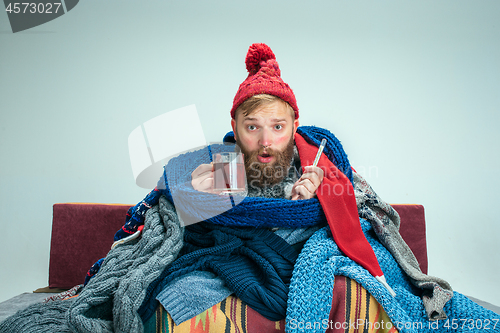 Image of Bearded Man with Flue Sitting on Sofa at Home. Healthcare Concepts.