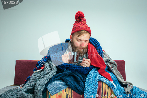 Image of Bearded Man with Flue Sitting on Sofa at Home. Healthcare Concepts.