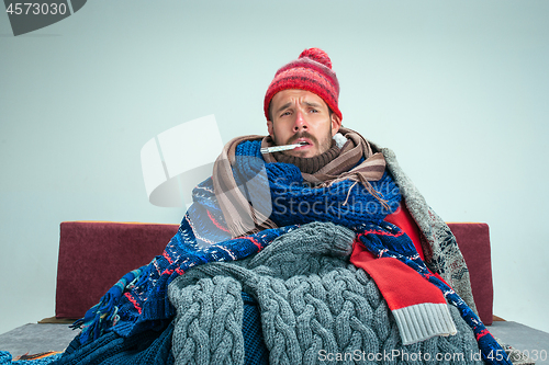 Image of Bearded Man with Flue Sitting on Sofa at Home. Healthcare Concepts.