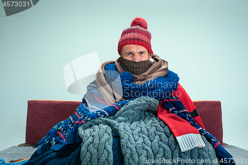 Image of Bearded Man with Flue Sitting on Sofa at Home. Healthcare Concepts.