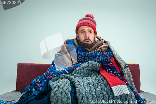 Image of Bearded Man with Flue Sitting on Sofa at Home. Healthcare Concepts.