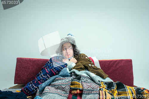 Image of The young woman with Flue Sitting on Sofa at Home. Healthcare Concepts.