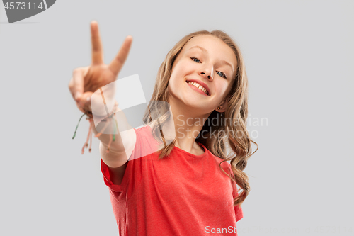 Image of smiling teenage girl in red t-shirt showing peace