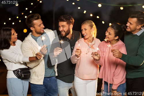 Image of happy friends with sparklers at rooftop party