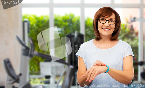 Image of smiling senior woman with fitness tracker over gym