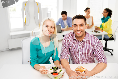 Image of happy colleagues having lunch and eating at office