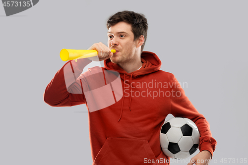 Image of football fan with soccer ball blowing horn