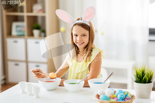 Image of girl coloring easter eggs by liquid dye at home