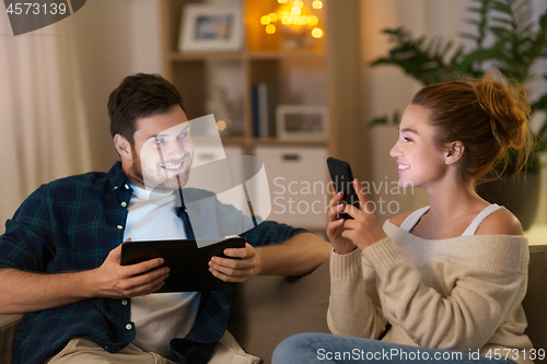 Image of couple with tablet computer and smartphone at home