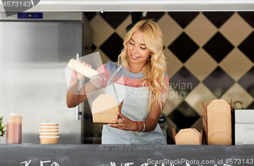 Image of happy saleswoman making wok at food truck