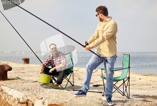 Image of happy friends with fishing rods on pier