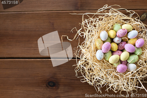 Image of easter eggs in straw nest on wooden table